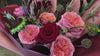 Un bouquet floreale in rotazione con rose rosse, peonie rosa, girasoli e cardi